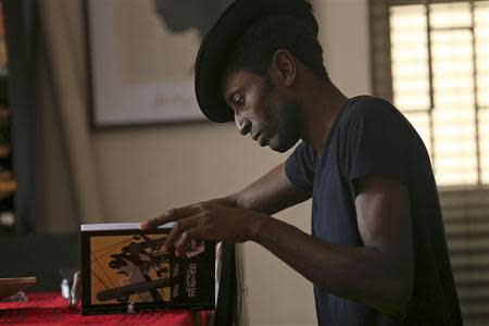 Nigerian musician Keziah Jones reads after an interview with Reuters at his home in Lagos February 25, 2014. REUTERS/Akintunde Akinleye