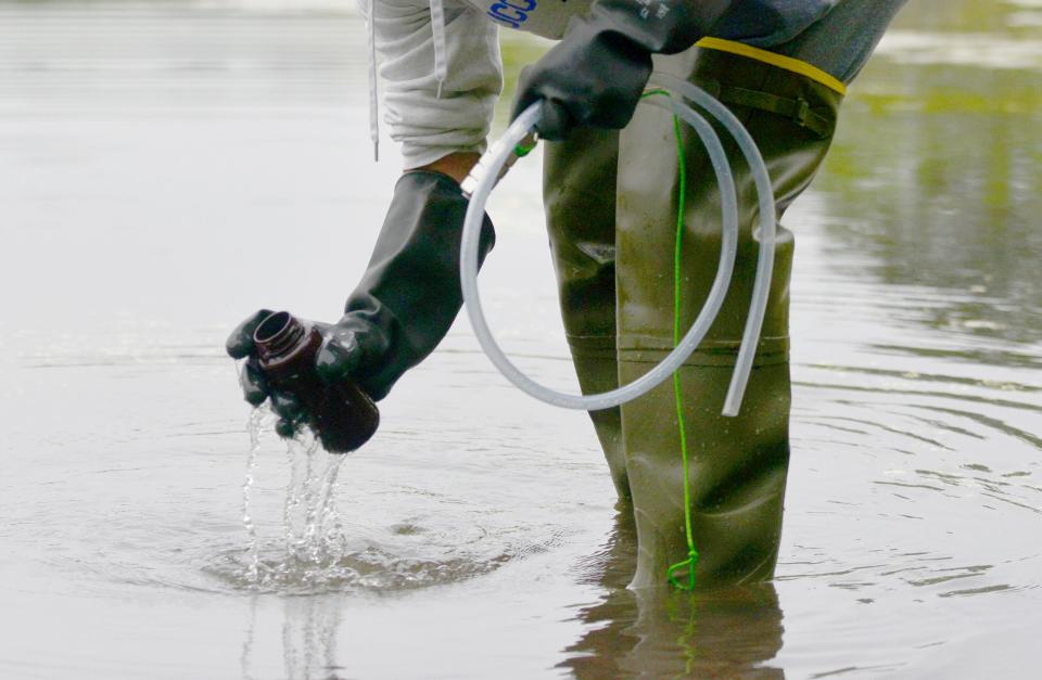 Association to Preserve Cape Cod intern James Marino dips a bottle on Thursday into the West Reservoir in West Harwich in preparation for water sampling.