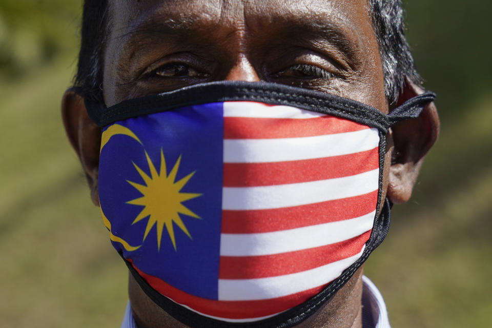 A supporter of People's Justice Party wearing a national flag face mask as he gathers with others outside the National Palace in Kuala Lumpur, Malaysia, Wednesday, Feb. 26, 2020. Malaysia's ruling alliance collapsed this week after 94-year-old Prime Minister Mahathir Mohamad resigned and dozens of lawmakers defected in an audacious attempt to form a new government. The political earthquake occurred less than two years after the alliance won a historic election that ousted a corruption-tainted coalition that had ruled for 61 years. (AP Photo/Vincent Thian)