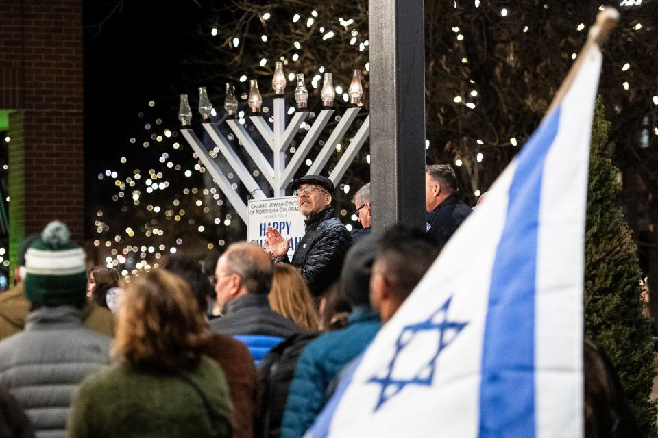 Rabbi Yerachmiel Gorelik sings with children on stage during a Menorah lighting ceremony in Old Town Square Fort Collins Monday.