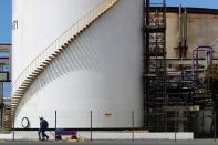 Workers pass in front of a tank at a chlorine-soda plant of the petrochemical company Braskem in Maceio