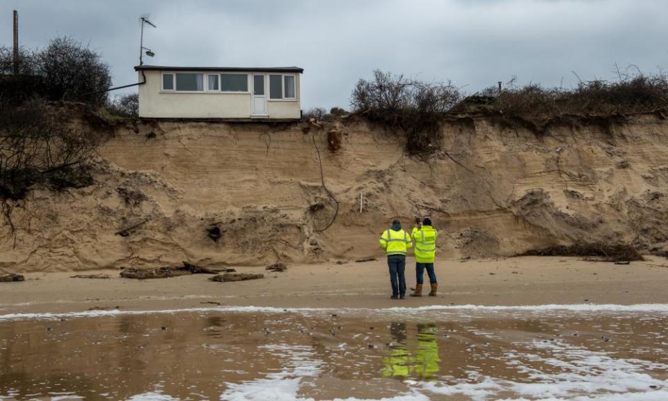 Building control surveyors on Hemsby beach in front of houses that have been evacuated.