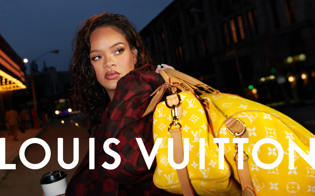 RiHanna holds two yellow luggage bags with the classic Louis Vuitton pattern. (Courtesy Louis Vuitton)