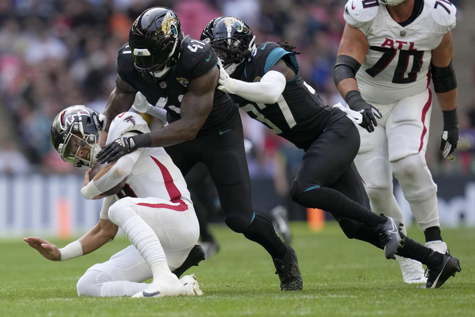 Atlanta Falcons quarterback Desmond Ridder (9), left, is sacked by Jacksonville Jaguars linebacker Josh Allen (41) and Jacksonville Jaguars tight end Evan Engram (17), right, during the first quarter of an NFL football game between the Atlanta Falcons and the Jacksonville Jaguars at Wembley stadium in London, Sunday, Oct. 1, 2023. (AP Photo/Kirsty Wigglesworth)