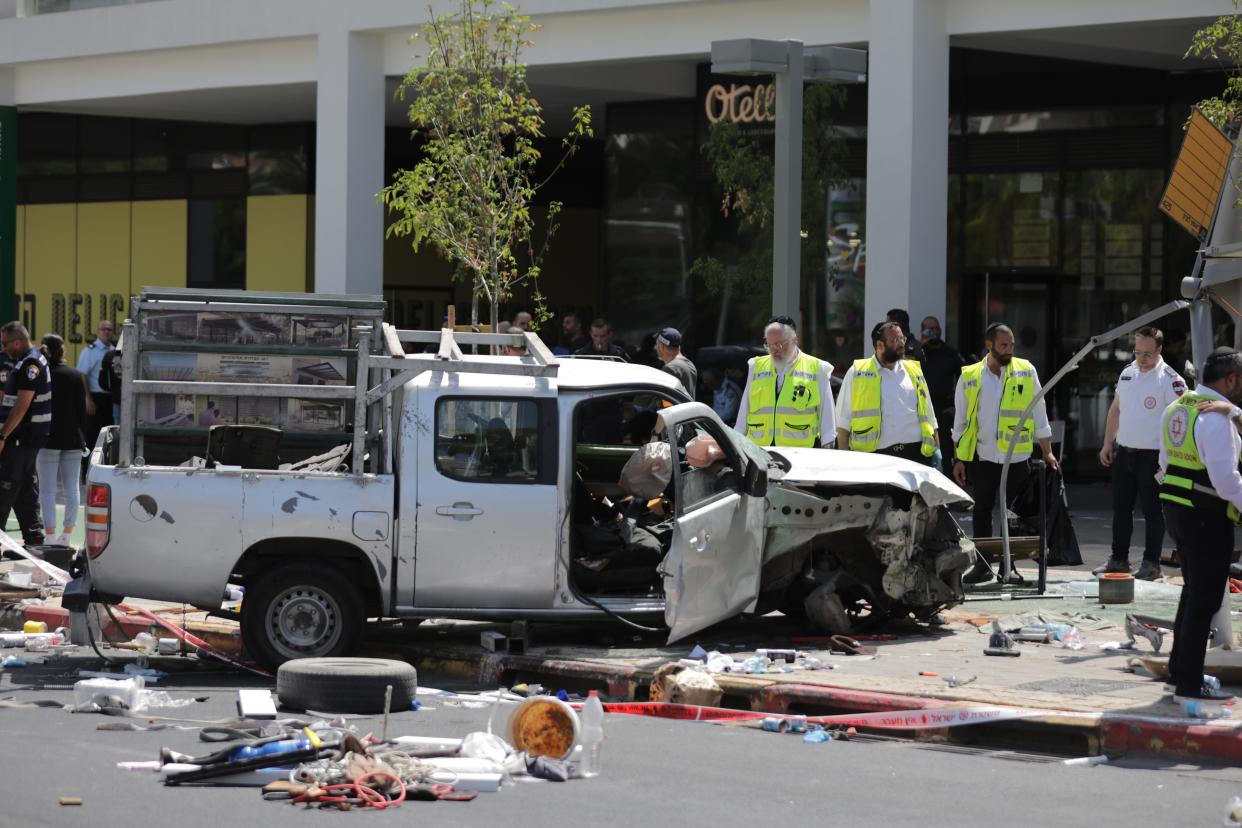 Israeli security forces and emergency workers stand near the site of a car ramming attack (EPA)