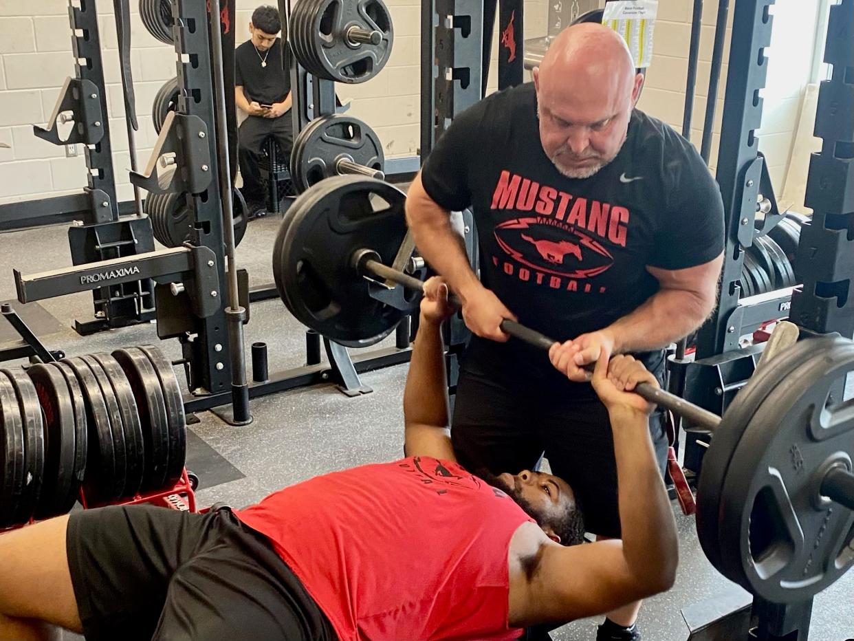 Manor football coach James Keller spots for JT Thomas inside the weight room on May 7, 2024. Thomas, the valedictorian of the senior class, will go to the Air Force Academy in the fall.
