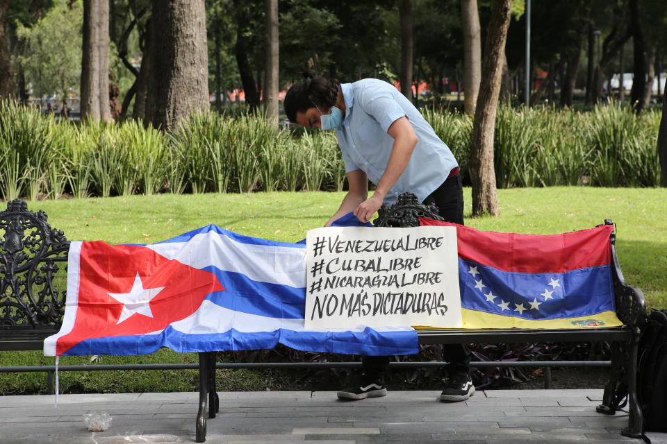 A Cuban man arranges a Cuban flag next to a Venezuelan national flag during a small demonstration in Alameda Park against the participation of Venezuela’s President Nicolas Maduro in the Community of Latin American and Caribbean States, CELAC, summit in Mexico City, Saturday, Sept. 18, 2021. CELAC has only existed for 10 years and is more left-leaning, having remained on good terms with countries including Cuba, Venezuela and Nicaragua. (AP Photo/Ginnette Riquelme)