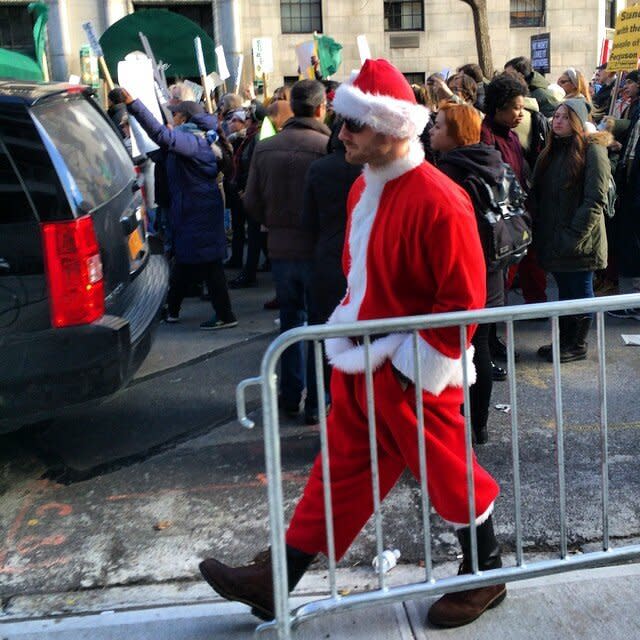 A man dressed up as Santa for SantaCon walk by protesters on 5th Ave. on Dec. 13, 2014 in New York City. 