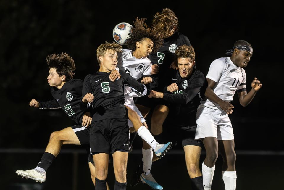 Players from Aurora and Kent Roosevelt leap to hit the ball off a corner kick during Tuesday night’s soccer match at Aurora High School.