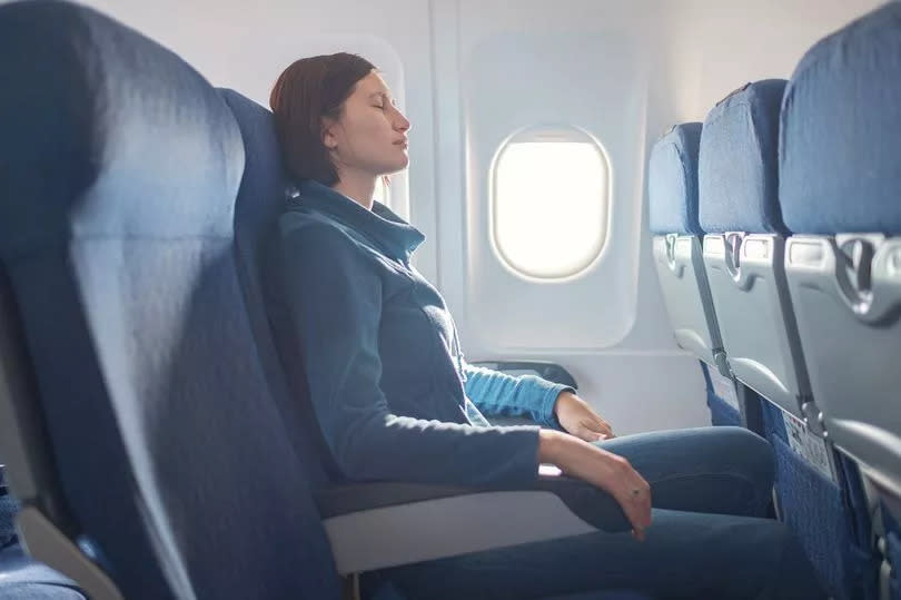 An image of a woman sitting in a plane seat by a window