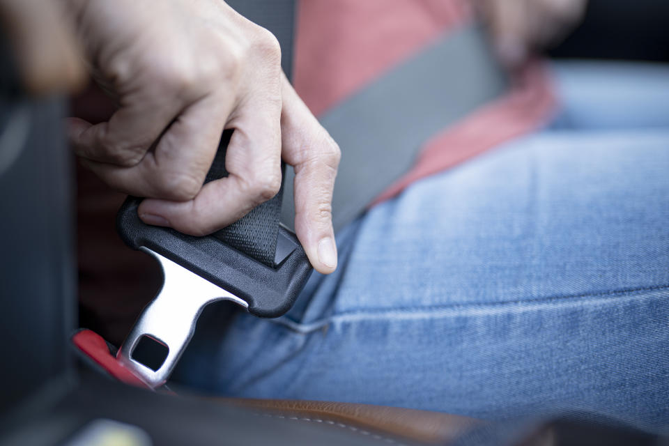 Close-up of a person fastening a seatbelt in a vehicle, promoting car safety