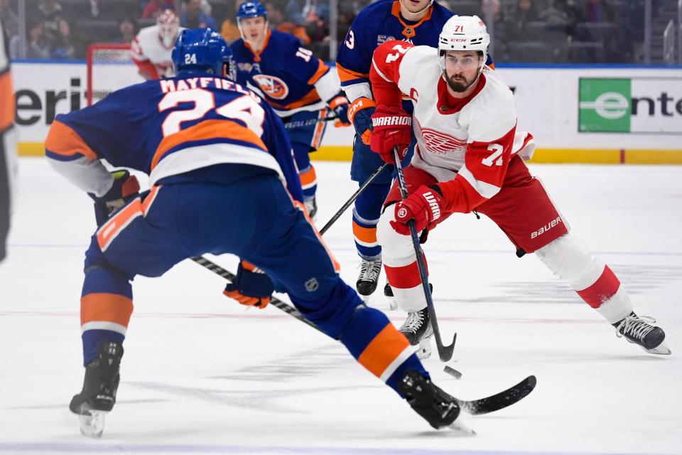 Detroit Red Wings center Dylan Larkin (71) skates with the puck defended by New York Islanders defenseman Scott Mayfield (24) during the first period at UBS Arena in Elmont, New York, on Friday, Jan. 27, 2023.