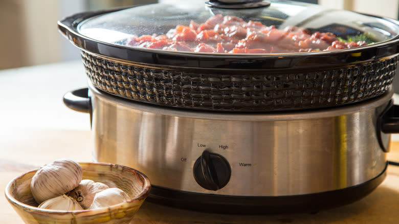 Beef stew in slow cooker with bowl of onions