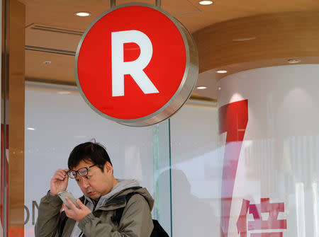 A man uses a mobile phone in front of a Rakuten Mobile branch in Tokyo, Japan December 14, 2017. REUTERS/Kim Kyung-Hoon
