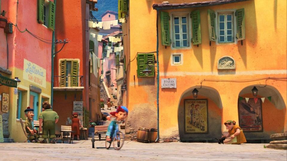 A redhaired girl rides her bicycle pulling a cart attached to the bike.