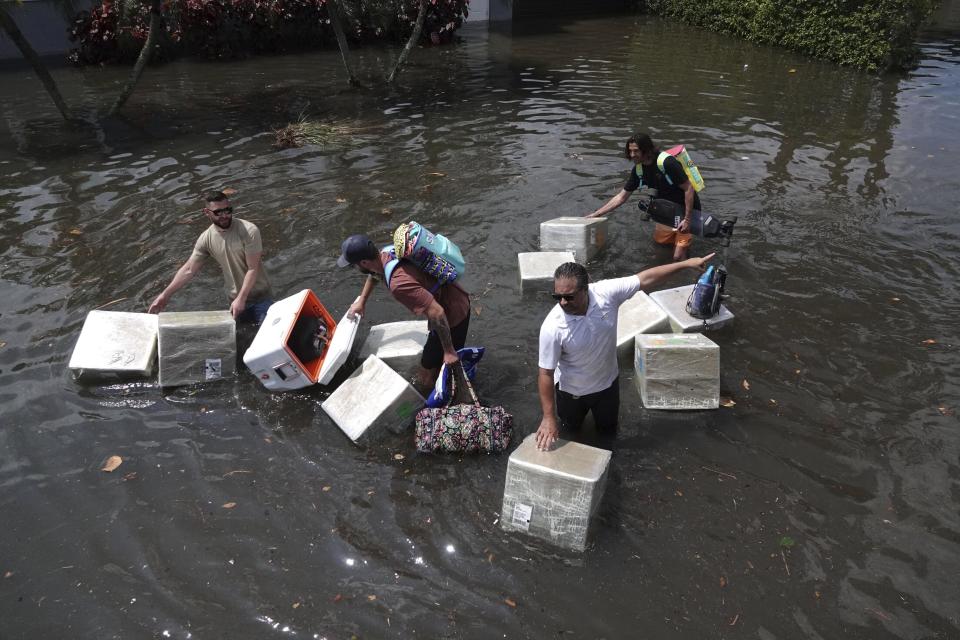 FILE - People try and save valuables as they wade through flood waters in the Edgewood neighborhood of Fort Lauderdale, Fla., April 13, 2023. Over 25 inches of rain fell in South Florida since Monday, causing widespread flooding. (Joe Cavaretta/South Florida Sun-Sentinel via AP)