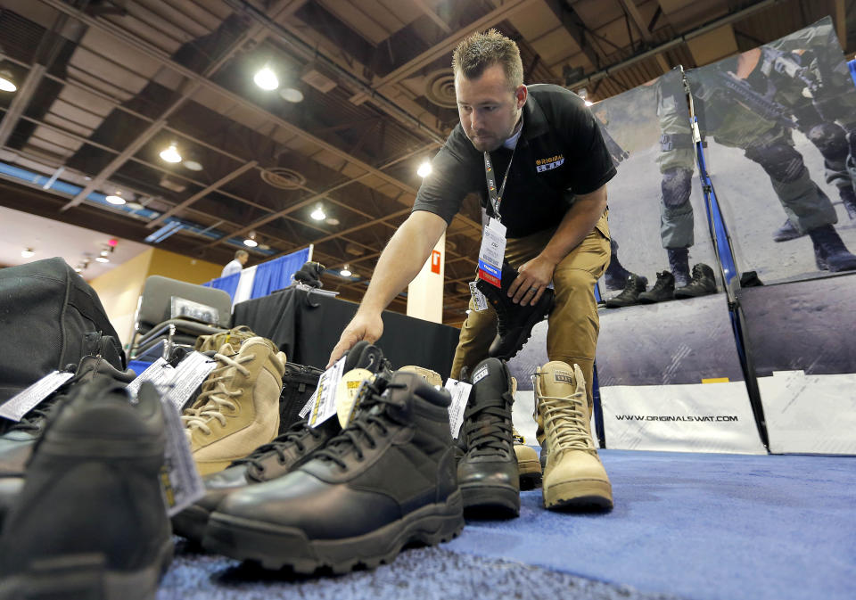 Josh Krause, of Original SWAT, prepares tactical footwear for display at the 8th annual Border Security Expo, Tuesday, March 18, 2014 in Phoenix. The two day event features panel discussions, sharing intelligence, and exhibitors displaying high-tech wares aimed at securing lucrative government contracts and private sales. (AP Photo/Matt York)