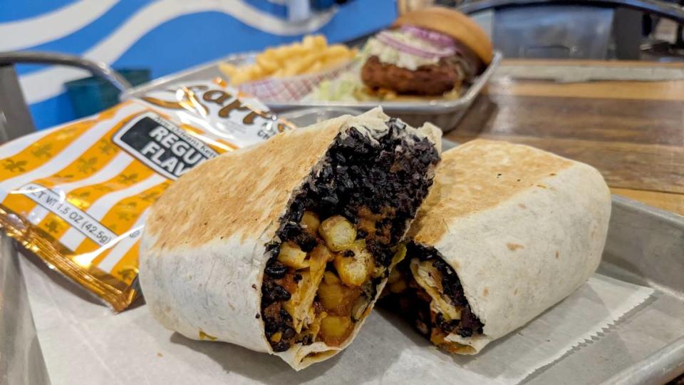 Gunther is a flour tortilla filled with chickpea curry, black rice, spinach and cucumber mint sauce. Phoebe (in background) is a sweet soy glazed tofu patty with lettuce, kimchi, onion and gochujang aioli on a bun. Both are new seasonal offerings at Old Bakery Beer.