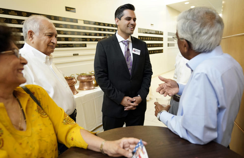 In this Sunday, July 29, 2018, photo, Democrat for Congress candidate Sri Kulkarni, center, listens to supporters attending a fundraiser for him in Houston. Kulkarni is running against Republican U.S. Rep. Pete Olson. (AP Photo/David J. Phillip)