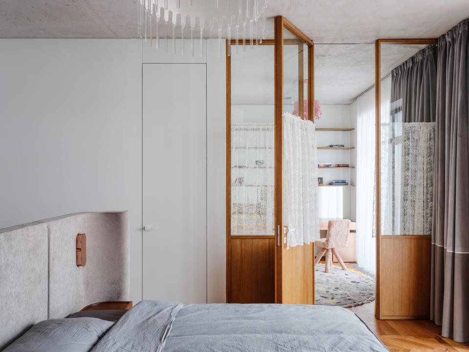 A simple bedroom with an intricate metal chandelier leads into Chilingarova's supersized closet, complete with a furry pink chair.