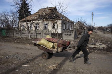 A man pulls a wheelbarrow past a house damaged by fighting in the town of Debaltseve February 25, 2015. REUTERS/Baz Ratner