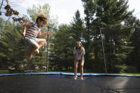 Logan Strauss, 5, bounces on the family's trampoline with his sister Samantha at their home in Basking Ridge, N.J., Wednesday, July 28, 2021. Logan's parents are keeping him out of school until he gets the COVID-19 vaccine. (AP Photo/Mark Lennihan)