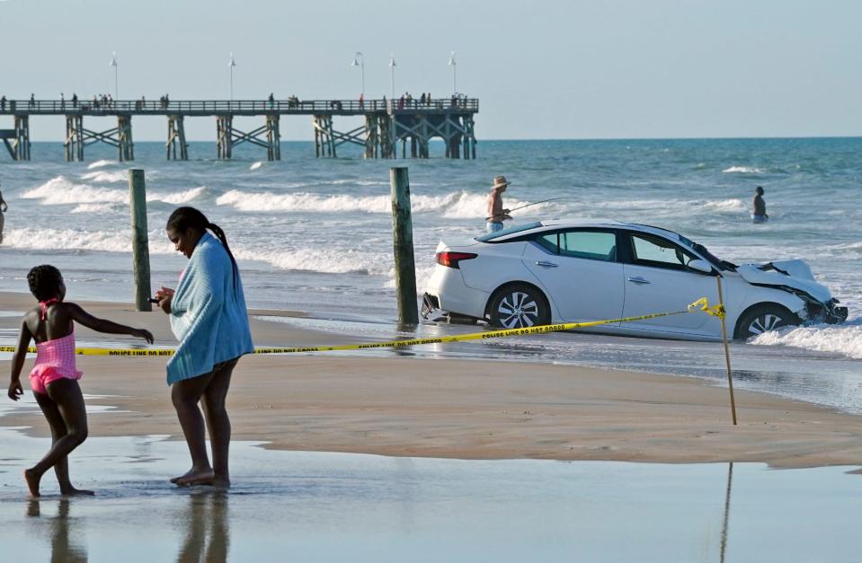 A car sits in the Atlantic Ocean after crashing through the empty toll booth at the International Speedway Boulevard beach approach in Daytona Beach, Fla.