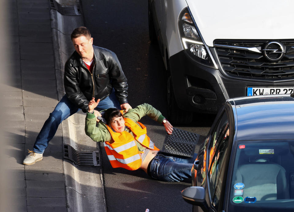 Ein Autofahrer zieht einen Straßenblockierer der Letzten Generation eigenhändig von der Fahrbahn in Berlin (Bild: REUTERS/Christian Mang)