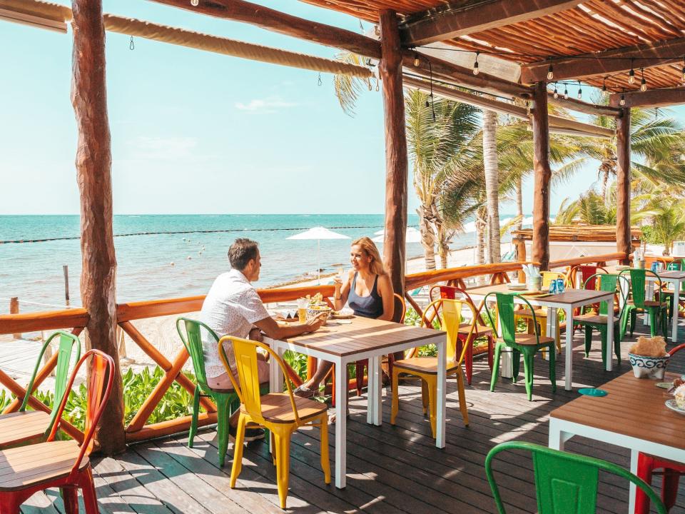 two people dining in an outdoor restaurant overlooking the beach and oceam