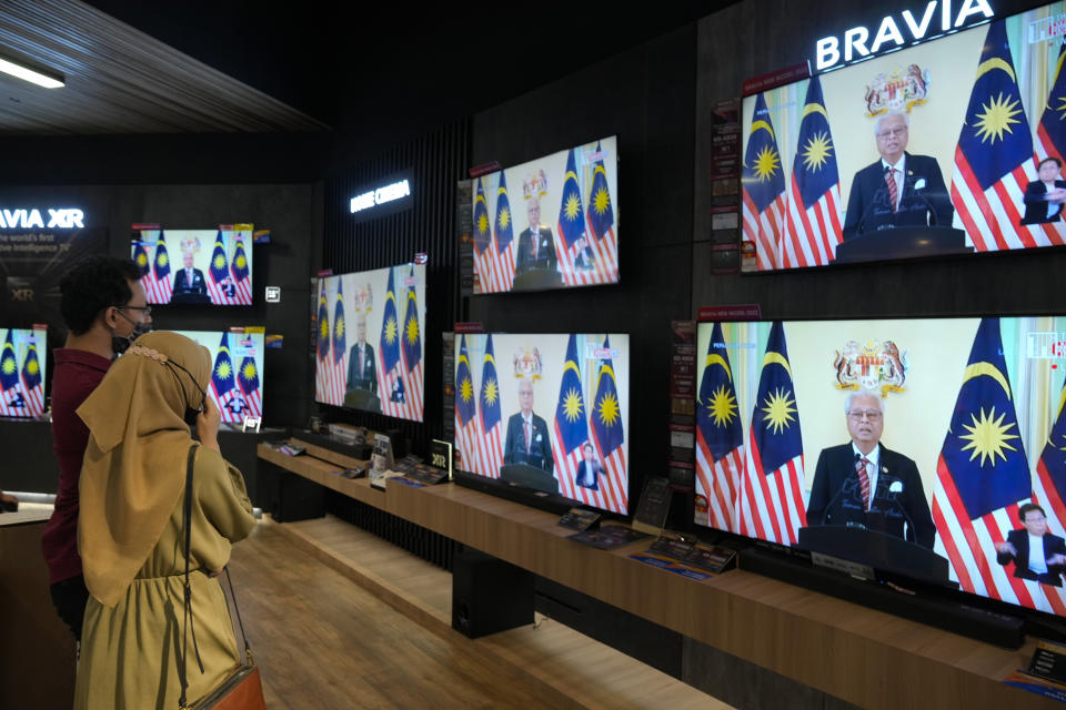 Customers watch a live broadcast of an announcement by Malaysian Prime Minister Ismail Sabri Yaakob at an electronics store in Kuala Lumpur, Monday, Oct. 10, 2022. Ismail announced Monday that Parliament will be dissolved, paving the way for general elections. (AP Photo/Vincent Thian)
