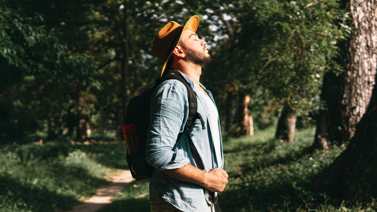  Man breathing deeply while hiking in forest. 