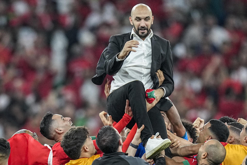 Los jugadores de Marruecos llevan en andas al técnico Walid Regragui tras la victoria sobre Portugal en los cuartos de final del Mundial en el estadio Al Thumama de Doha, Qatar, sábado 10 de diciembre, 2022. (AP Footo/Ariel Schalit)