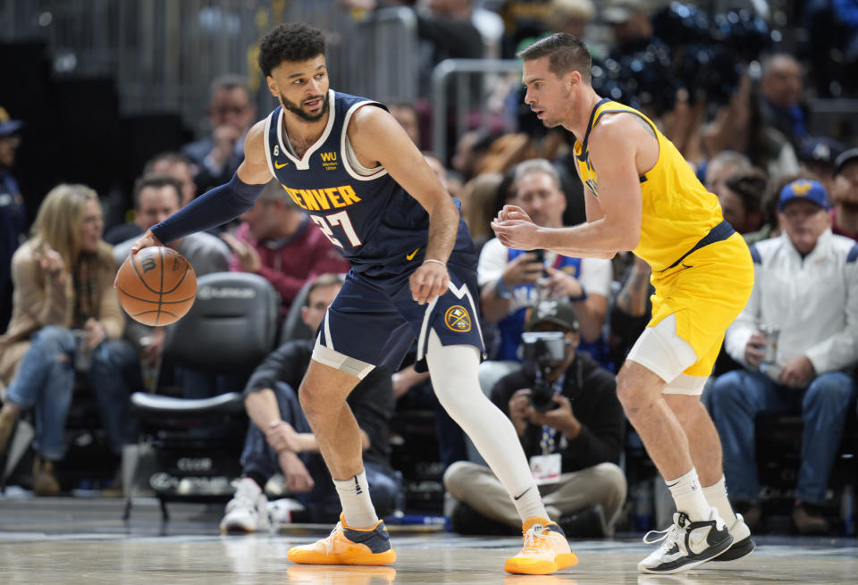 Denver Nuggets guard Jamal Murray, left, looks to pass the ball as Indiana Pacers guard T.J. McConnell defends in the first half of an NBA basketball game Friday, Jan. 20, 2023, in Denver. (AP Photo/David Zalubowski)