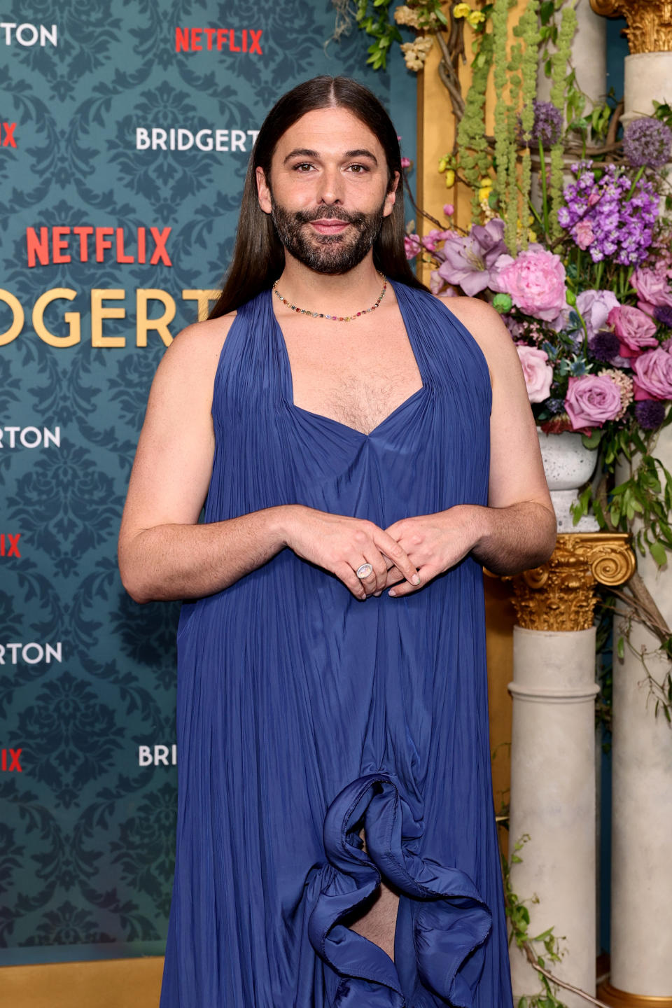 Jonathan Van Ness wearing a flowing dress on the red carpet for a Netflix and Bridgerton event