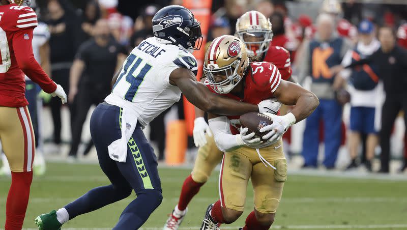 San Francisco 49ers linebacker Fred Warner, right, returns an interception against Seattle Seahawks wide receiver DK Metcalf during the second half of an NFL football game in Santa Clara, Calif., Sunday, Dec. 10, 2023.
