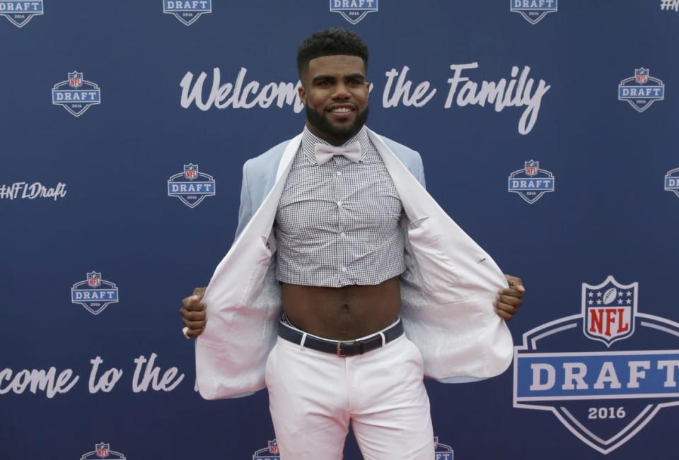 Ohio State’s Ezekiel Elliott poses for photos upon arriving for the first round of the NFL football draft April 28, 2016, in Chicago. Elliott stunned on the red carpet when he unbuttoned his suit jacket to reveal his bare, toned abs, raising the bar for draft night fashion surprises. (AP Photo/Nam Y. Huh, File)