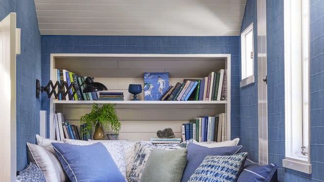 a bed with blue pillows and bookcase