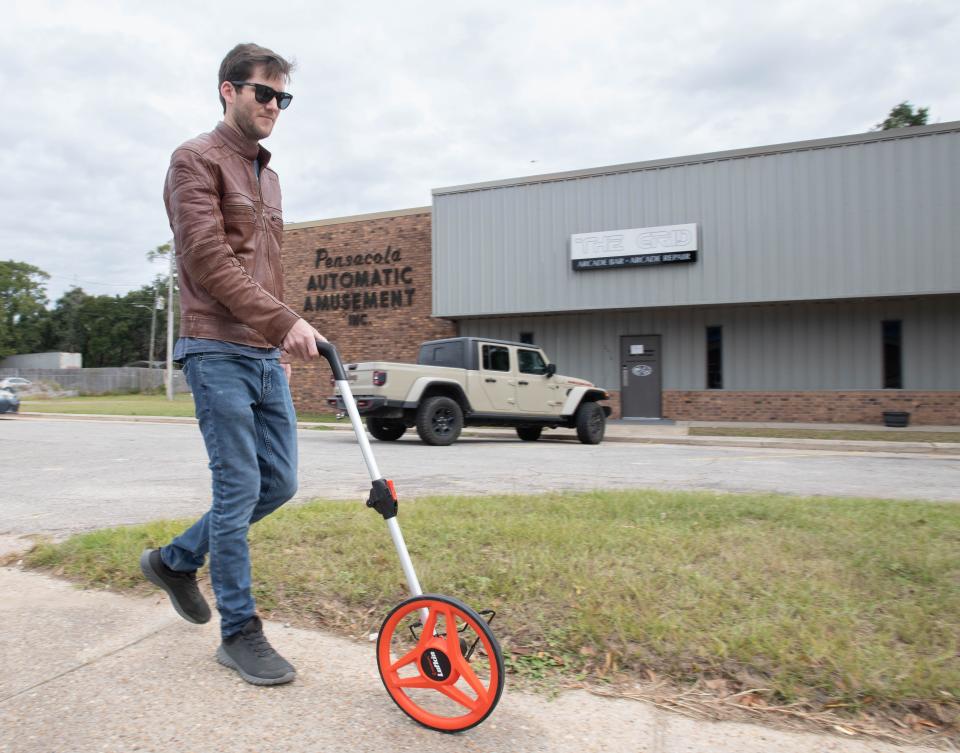 Owner Daniel Demeter measures the distance from The Grid Arcade Bar to a daycare center down the road on North Pace Boulevard in Pensacola on Tuesday, Nov. 22, 2022.