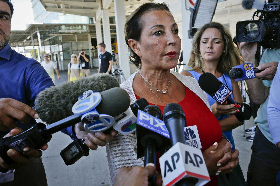 Raghida Dergham, center, a senior diplomatic reporter at the United Nations updates reporters about her flight aboard an Emirates airline after an emergency was declared when the plane landed at JFK Airport with ill passengers on a flight from Dubai, Wednesday Sept. 5, 2018, in New York. (AP Photo/Bebeto Matthews)