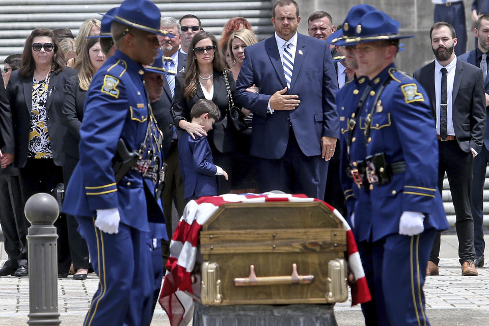 Edwin Edwards' wife Trina and son Eli, 7, center, watch as the flag-draped casket of the former Louisiana Gov. is taken from the Louisiana State Capitol to a waiting horse-drawn carriage by members of the Louisiana State Police in Baton Rouge, La., Sunday, July 18, 2021. A processional featuring a law enforcement motorcade and the Southern University Marching Band was held though the streets of downtown Baton Rouge, ending at the Old State Capital building where a private funeral service was held. The colorful and controversial four-term governor died of a respiratory illness on Monday, July 12th at the age of 93. (AP Photo/Michael DeMocker)