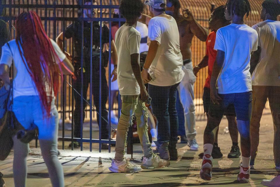 People gather around as police attend to a person after gun shots rang out during a high school football game between Del City and Choctaw in Choctaw, Okla. on Friday, Aug. 25, 2023.