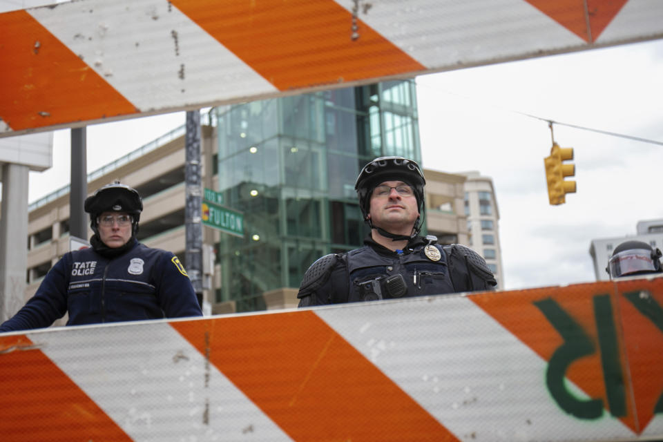 Police officers look towards protesters from behind a barricade in front of the Van Andel Arena in downtown Grand Rapids, Mich., on Saturday, April 16, 2022. Activists have held protests for four straight days since the release of a video showing 26-year-old Congolese immigrant Patrick Lyoya being shot and killed by a Grand Rapids police officer while resisting arrest during a traffic stop on April 4. (Daniel Shular/The Grand Rapids Press via AP)