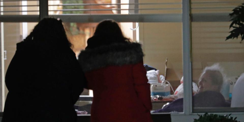 Susan Hailey, 76, at right in background, who has tested positive for the new coronavirus, visits through a window with her daughters, Tuesday, March 10, 2020, at the Life Care Center in Kirkland.