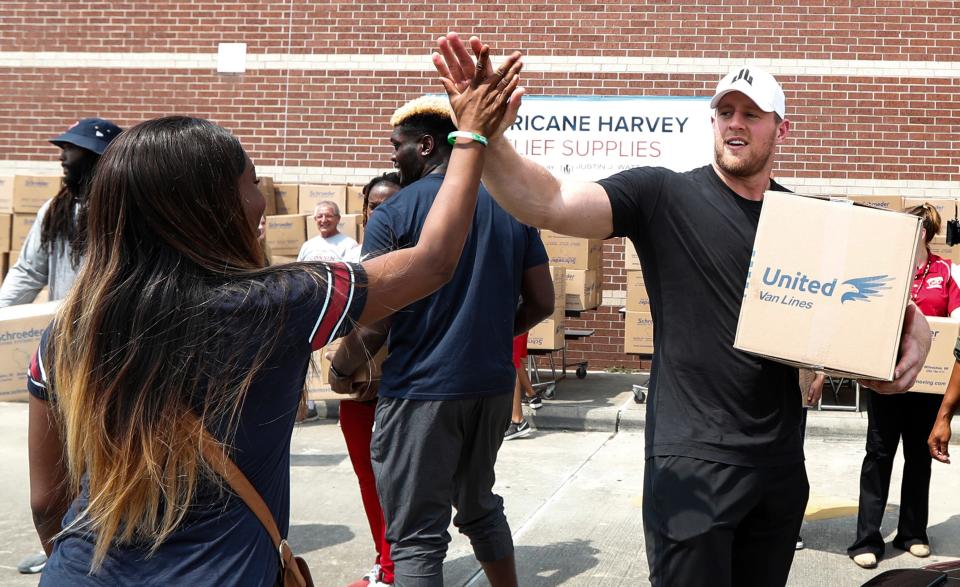 Anna Ucheomumu (left) high-fives Houston Texans defensive end J.J. Watt after loading a car with relief supplies to help people impacted by Hurricane Harvey in Houston on Sept. 3, 2017.