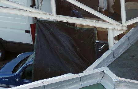 A French gendarme (top partially hidden) works on a oversized crate in the cargo area of the airport in Saint-Denis on the French Indian Ocean island of La Reunion, July 31, 2015. REUTERS/Zinfos974/Prisca Bigot