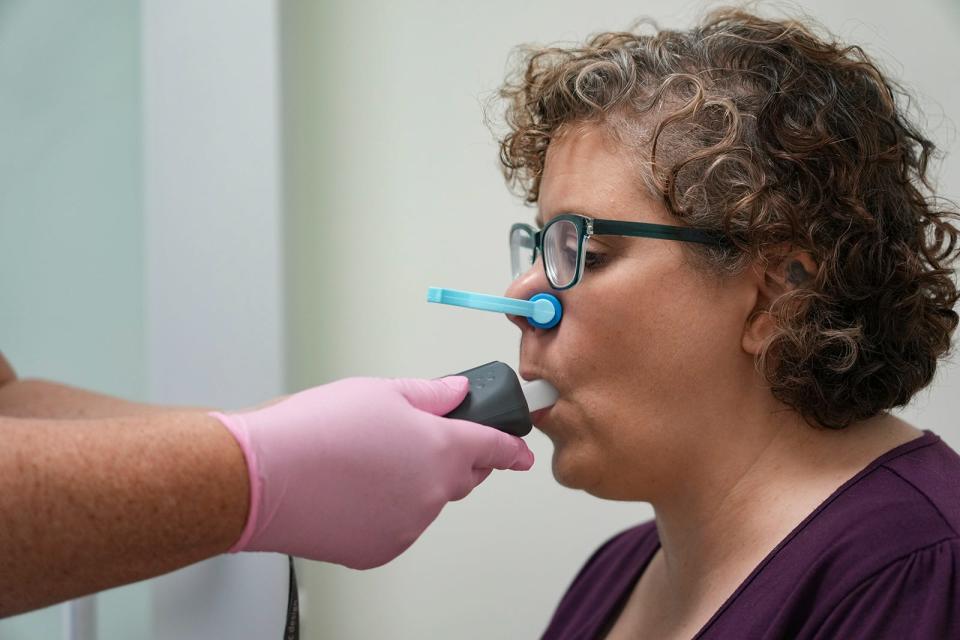 Jenna Bert breathes into a spirometer to measure the volume of air inspired and expired by the lungs. ALS is a neuromuscular disease, which means it can affect breathing.