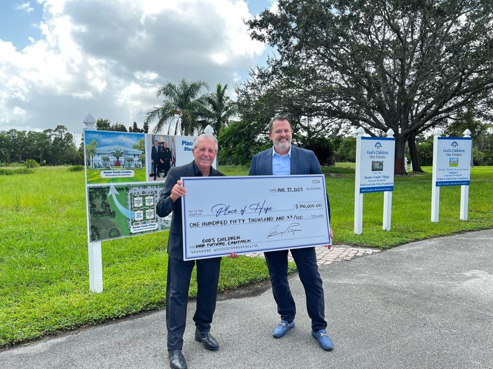 Gary Player (left) and Charles Bender III (right) pose with a $150,000 check from the Gary and Vivienne Player Foundation on Aug. 22, at 1940 SE Cove Rd in Stuart, Fla.