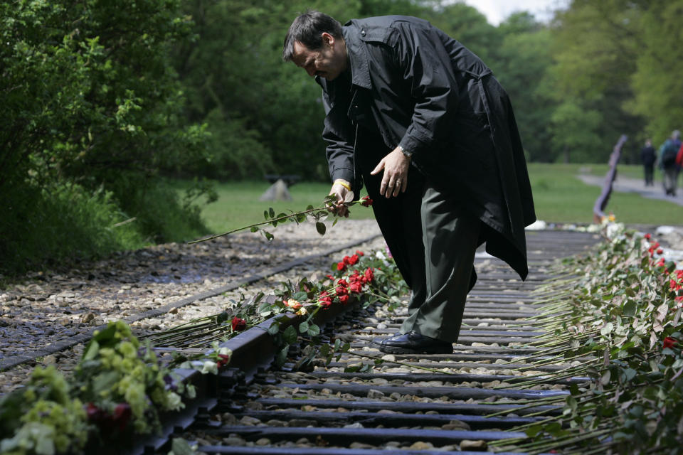In this Monday May 9, 2015, file photo, a man puts a rose on the railroad tracks at former concentration camp Westerbork, the Netherlands, remembering more than a hundred thousand Jews who were transported from Westerbork to Nazi death camps. The Dutch national railway company NS says it will set up a commission to investigate how it can pay individual reparations for its role in mass deportations of Jews by Nazi occupiers during World War II. (AP Photo/Peter Dejong)