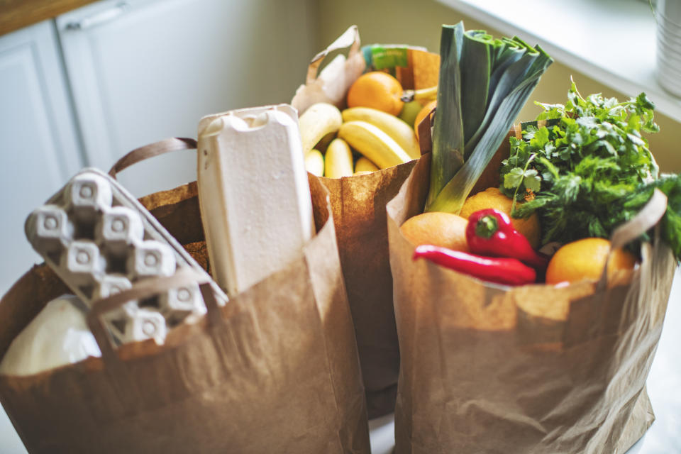 Brown paper shopping bags full of produce and eggs