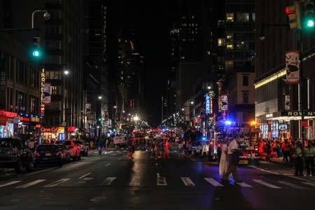 People walk near Times Square area after power was restored following a blackout that affected buildings and traffic during widespread power outages in the Manhattan borough of New York